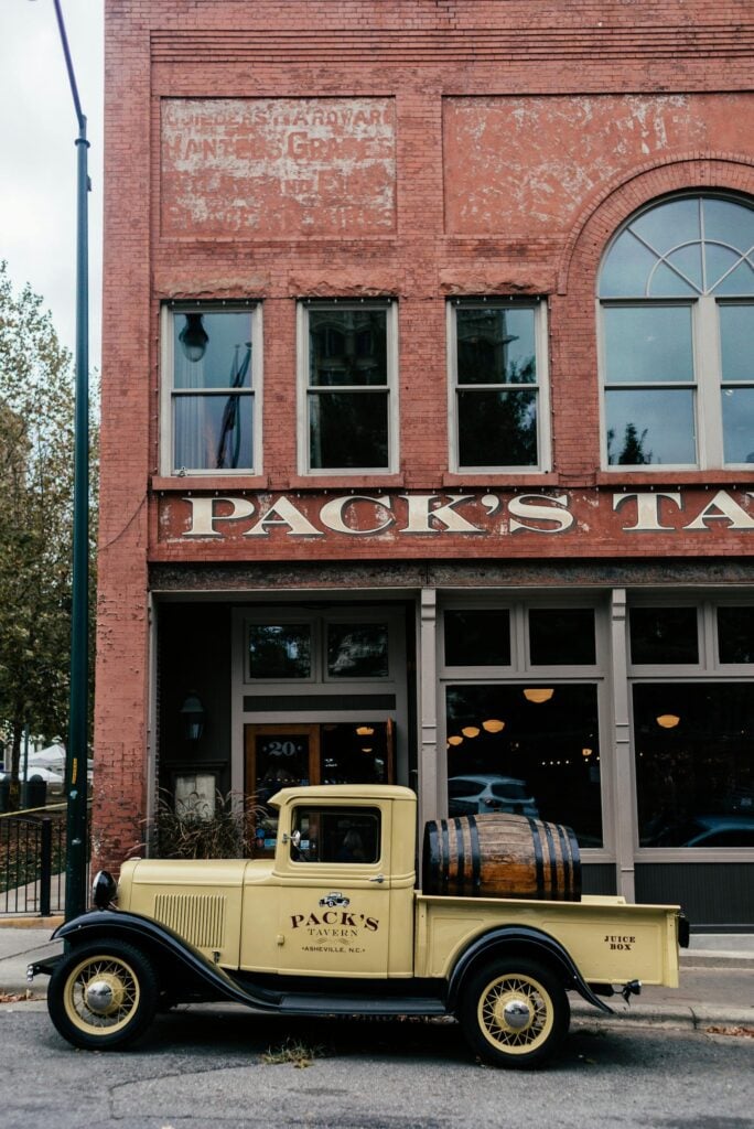 A classic vintage truck parked outside a historic tavern with red brick facade.