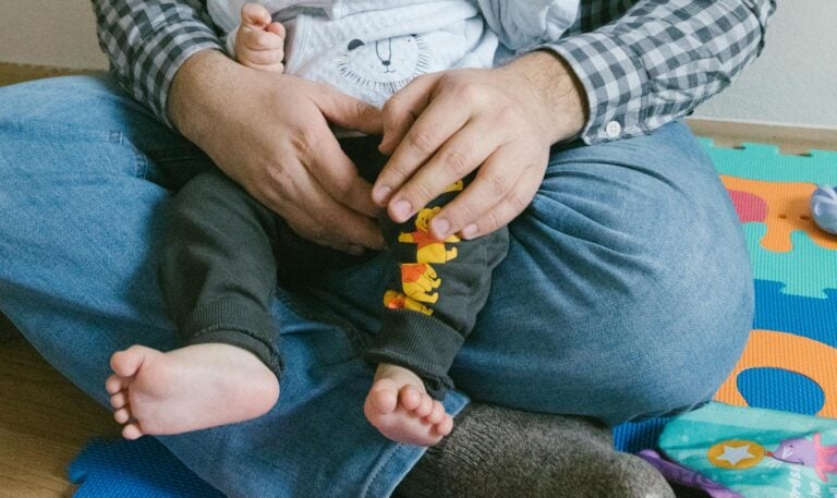 A joyful moment of a father and baby bonding in a playroom setting.