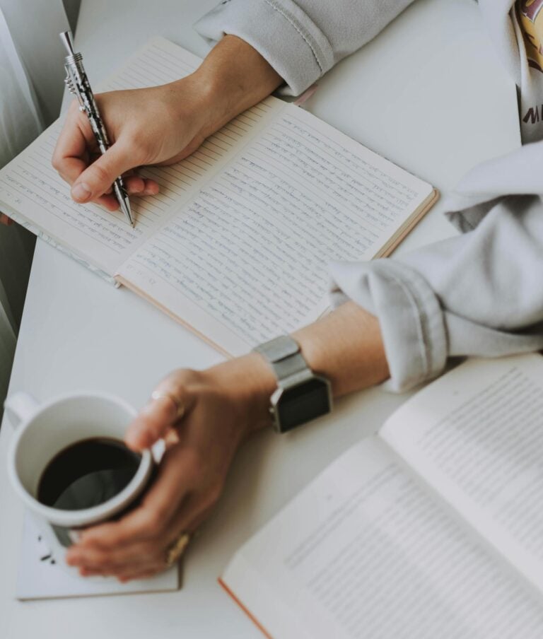 Hands writing in journal, metaphor for clarity in CBT.