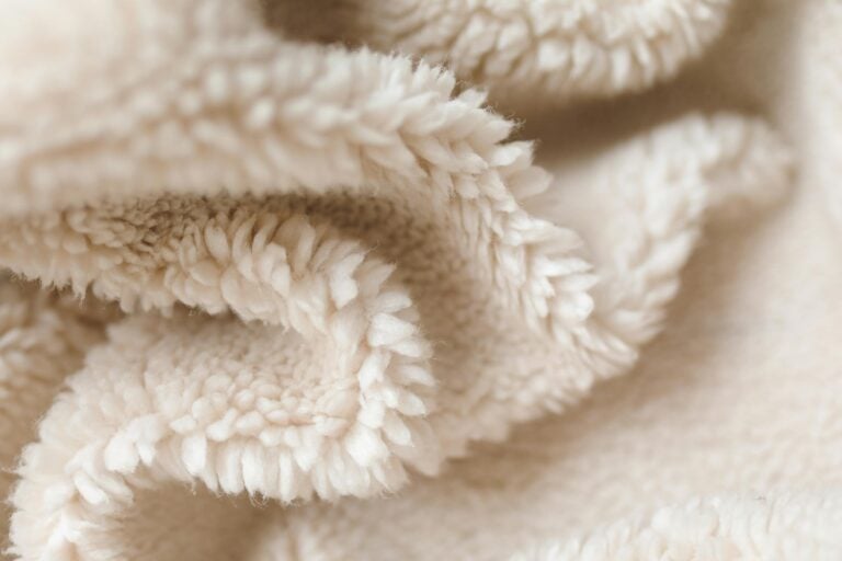 Detailed texture of a soft beige fabric blanket, showcasing fleece material.
