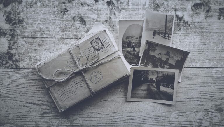 Flatlay of vintage letters tied with twine and black and white photos on a wooden surface.