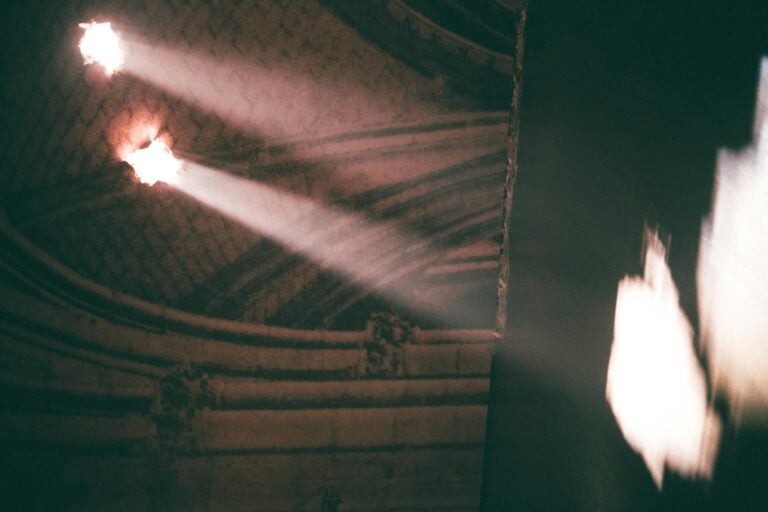 Sunlight streams through a gothic architectural hallway, creating an eerie ambiance.